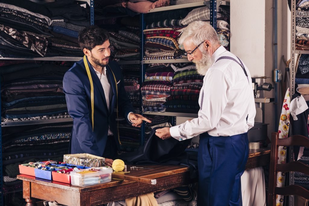 young male fashionmdesignern showing blue fabric his customer shop scaled