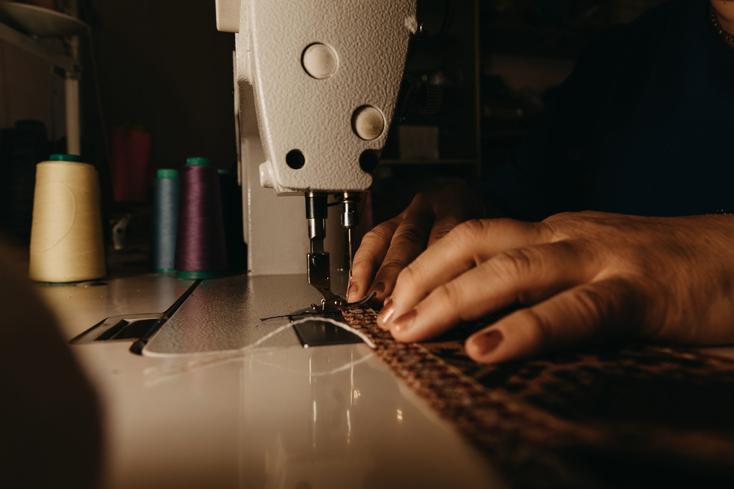 Professional tailor using a sewing machine to stitch uniform fabric
